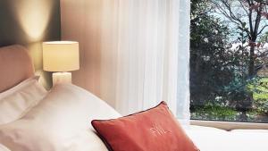 阿罗纳FWL Italian Romance on the Lake的窗边的白色沙发,上面有红色枕头