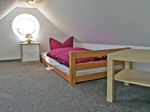 KröslinFerienwohnung Le Papillon的一间卧室配有一张带粉红色枕头的床和一张桌子