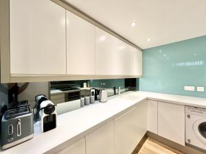 伦敦VIP SERVICED APARTMENTS LONDON ExCELLENT LOCATION GREAT PRICE的厨房配有白色橱柜、洗衣机和烘干机