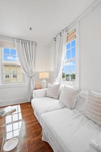 棕榈滩ORCHID SUITES - Historic Palm Beach Hotel Condominium的白色的客厅配有白色的沙发和2扇窗户。