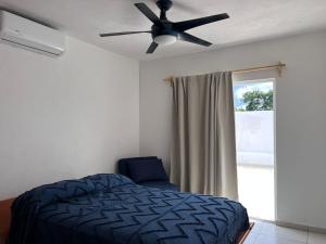 新巴利亚塔Villa Jardín的一间卧室配有吊扇、一张床和一个窗户。