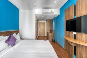 芽庄TK Nha Trang Hotel的一间卧室配有一张床和一台平面电视