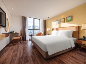 河内Nesta Hotel & Spa的酒店客房设有一张大床和一张书桌。