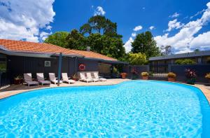卢拉Leura Gardens Resort的一个带椅子的游泳池以及一座房子