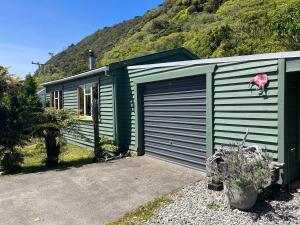GranityClassic Kiwi bach的一座带车库和山的绿色房子