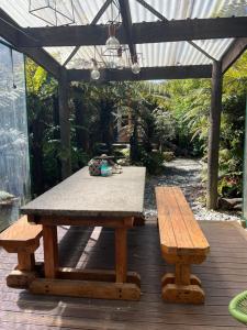GranityClassic Kiwi bach的木甲板上的一张野餐桌和两张长椅