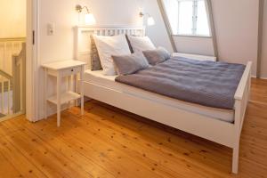弗伦斯堡Stadthaus Flensburg的卧室配有白色的床,铺有木地板
