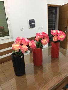 拉马萨un nouveau appartement avec un parking gratuit sur place的桌子上满是粉红色玫瑰的三瓶花