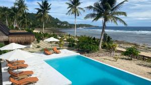 San IsidroYapak Beach Villas的一个带椅子的游泳池和海滩