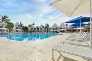 棕榈滩Courtyard by Marriott Aruba Resort的一个带躺椅和遮阳伞的游泳池