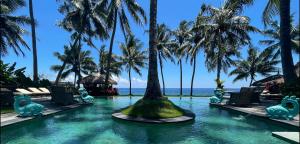 提安亚尔Louka Beach Bali的棕榈树和海洋度假村的游泳池