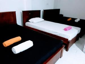 康提Black And White Kandy Guest House 01的客房内的两张床和毛巾