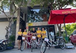 岘港Sontra Sea Hotel的一群穿着黄色衬衫的人站在自行车旁