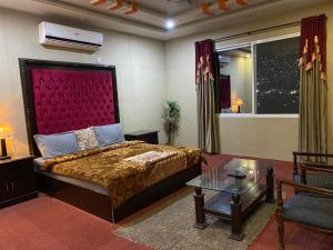 穆扎法拉巴德Kashmir lodge的一间卧室配有一张大床和红色床头板