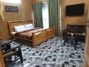 穆扎法拉巴德Kashmir lodge的一间卧室配有一张床、两把椅子和电视