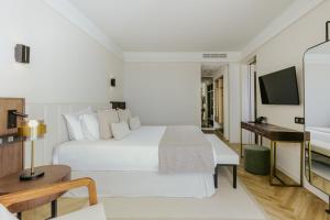普罗塔拉斯黄金海岸酒店 的酒店客房设有一张白色大床和一张书桌