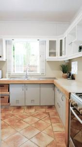 塔马兰Tamarin River Villa的厨房配有白色橱柜和瓷砖地板。