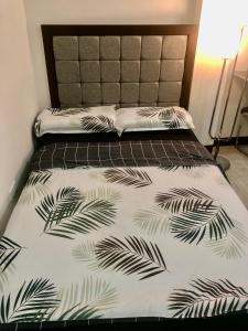 马尼拉JMC Homes的一张带黑色和白色床罩的床铺,上面有棕榈叶