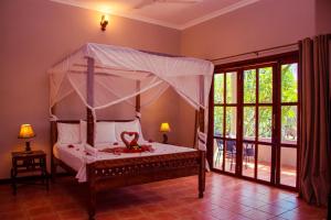 基济姆卡济Mandarin Resort Zanzibar的一间卧室配有一张带天蓬的床