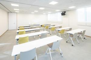 IeuraTeshima ESPOIR PARK的一个空的教室,有白色的桌子和黄色的椅子