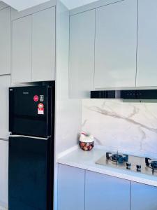 MukahEasy Homestay的厨房配有黑冰箱和白色橱柜。