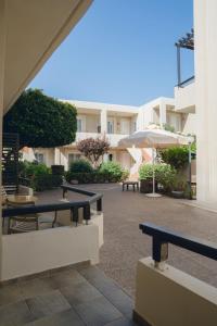 卡拉马基科琳娜马雷酒店的庭院配有长椅和桌子以及雨伞。
