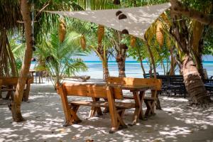 迪弗西Dhiffushi Inn的海滩上带遮阳伞的野餐桌