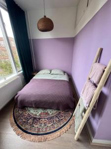 海牙IVY - Classical & modern apartment in lovely neighbourhood near beach的紫色卧室配有一张床和地毯