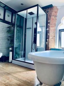 墨尔本Chapter Two - Melbourne的浴室配有白色浴缸和玻璃淋浴间。