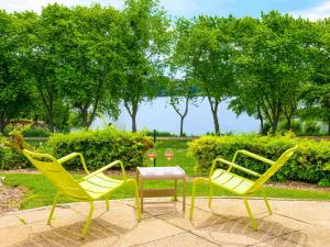 克雷泰伊诺富特巴黎克里特尔湖滨酒店的公园里三个黄色的椅子和一张桌子