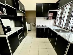 马六甲Rumah Mok Aji Homestay Melaka的一间小厨房,配有黑色橱柜和水槽