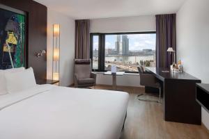 鹿特丹Maashotel Rotterdam Centre的配有一张床、一张书桌和一扇窗户的酒店客房
