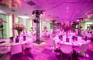 鹿特丹Mainport Hotel Rotterdam, a Hilton Affiliate Hotel的宴会厅配有白色桌椅和紫色照明