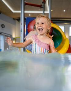 巴德瓦尔特斯多夫H2O Hotel-Therme-Resort, für Familien mit Kindern的一个小女孩在水里玩耍