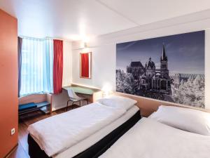 亚琛B&B Hotel Aachen-Hbf的酒店客房配有两张床和一张书桌