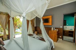 蓝梦岛Tropical Garden by TANIS的一间卧室设有天蓬床和一间浴室。