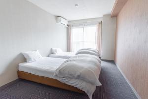 南鱼沼市CHENDA INTERNATIONAL HOTEL的一间卧室设有两张带白色床单的床和窗户。
