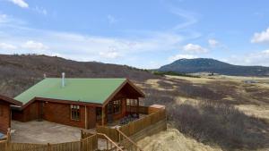 ÚthlidSummer House with Stunning Mountain Views的田野上带绿色屋顶的小木屋