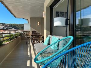 滨海托萨Magnificent apartment at the sea front of Tossa de Mar的阳台设有蓝色长椅,阳台上设有蓝色长椅。