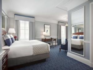 波士顿费尔蒙科普利广场酒店的酒店客房带一张床、一张书桌和一面镜子