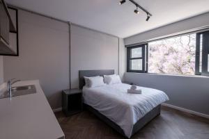 约翰内斯堡Inn & Out Plus Rosebank的卧室配有白色的床和窗户。