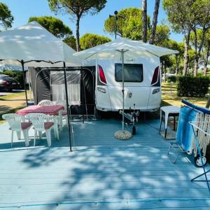 卡瓦利诺WMC BUSCHMANN camping-in-venedig Wohnwagenvermietung at UNION LIDO Cavallino的白色大篷车,配有帐篷和桌椅