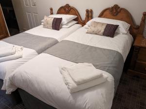 惠特比The Board Inn - Lealholm的卧室内的两张床,配有白色床单和枕头