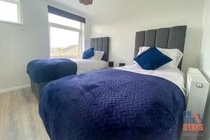 坎特伯雷OnSiteStays - Ideal Long Term Retreat, 2-BR House with Conservatory, Parking & Wi-Fi的一间卧室配有两张带蓝色枕头的床