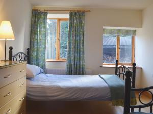 奥斯威斯Granary Cottage的一间卧室配有一张床、一个梳妆台和两个窗户。