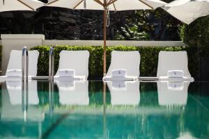 布宜诺斯艾利斯布宜诺斯艾利斯四季酒店的游泳池旁的四把白色椅子和一把遮阳伞
