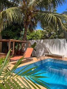 达喀尔Francesca Guest House的一个带椅子和棕榈树的游泳池