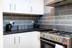格雷夫森德OnSiteStays - Contractor Friendly Retreat, 2-BR Terrace House near A2的厨房配有白色橱柜和炉灶。