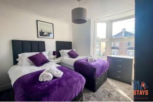 格雷夫森德OnSiteStays - Contractor Friendly Retreat, 2-BR Terrace House near A2的一间卧室设有两张带紫色床单的床和窗户。