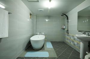 扶安Buan Tree California Hotel的浴室配有白色浴缸和水槽